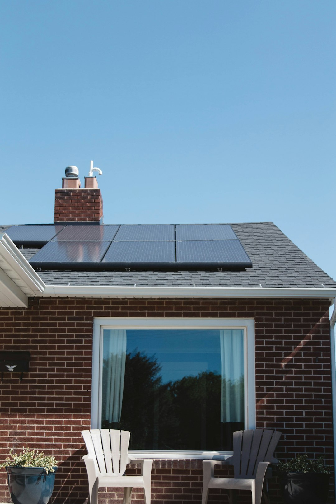 Mastering the First Impression: Your intriguing post title goes here Vivint Solar - Solar Panels on roof of brick home with window and Adirondack chairs.